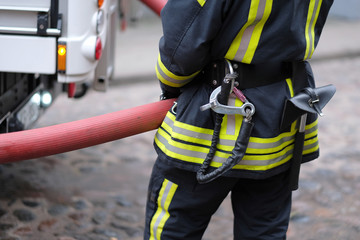 A member of the fire brigade holds a water supply hose from the fire engine