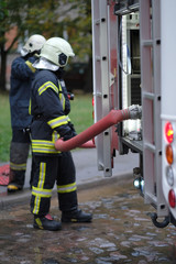 Fototapeta premium A member of the fire brigade holds a water supply hose from the fire engine