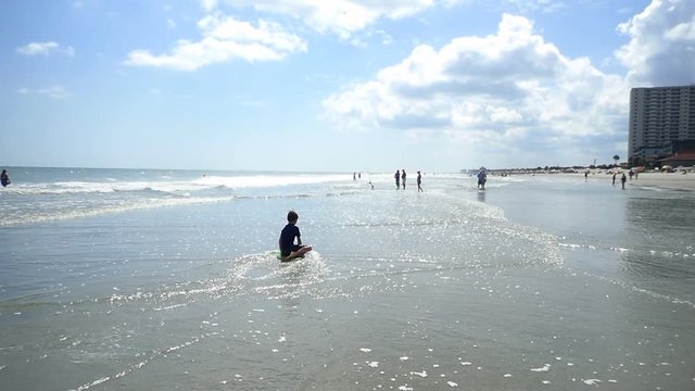 Little boy trying to learn how to skim board on vacation at Myrtle Beach