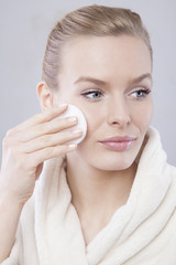 Beautiful girl is cleaning her face with tonic.