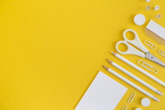 White office utensils on yellow background