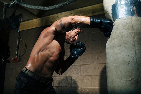 A boxer throws a hard punch at a punching bag in a gym