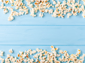 Popcorn horizontal banner. Kernels lying in form of frame on blue wooden background. Copy space. Top view.