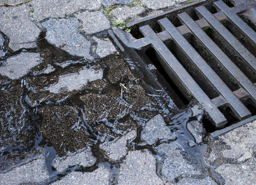 Wasser / Regenwasser fliesst in Kanalisation durch Gullideckel