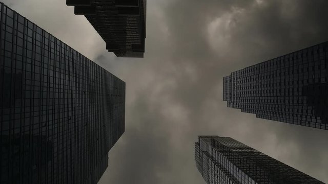 Dark clouds pass over over skyscrapers. Low angle time lapse.