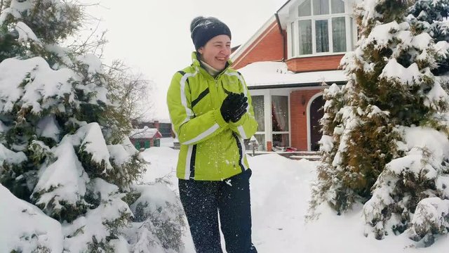4k footage of happy cheerful woman playing at backyard and throwing snow up in the air