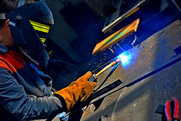 Industrial Worker labourer at the factory welding steel structure