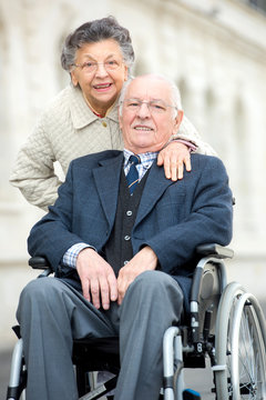 senior man being pushed by wife in wheelchair