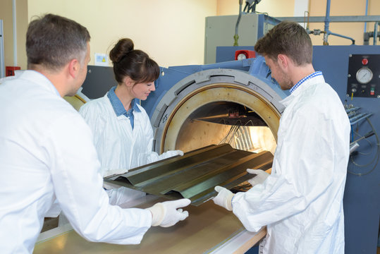 People entering corrugated metal into furnace