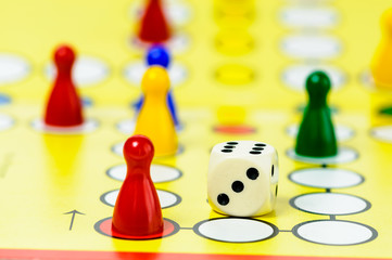 Pieces and a die on a Ludo board game