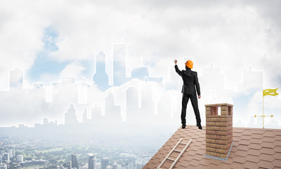 Man architect draw silhouette of modern city on blue sky. Mixed media