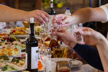 Hands clinking glasses with vodka at party