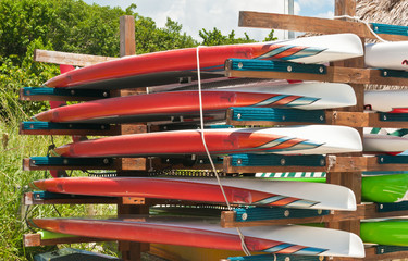 Colorful paddle boards / hanging on wood rack on a tropical beach on the Gulf of Mexico