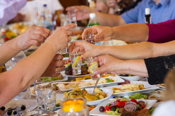 Hands clinking glasses with vodka at party