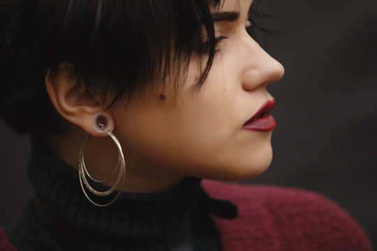 Closeup of unconventional woman portrait with tunnels on the ears and big earring