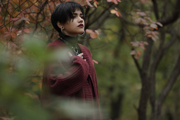 Unconventional woman portrait in marsala color cardigan with black leather sword belt