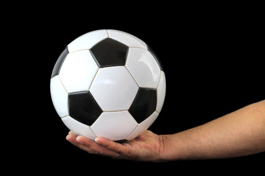 Soccer ball on a hand and black background