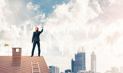 Man architect draw silhouette of modern city on blue sky. Mixed 