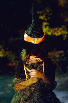 Young girl in witch costume in woods