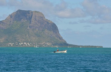 Obraz premium Pêcheur en barque, devant le Morne Brabant, montagne de l'île Maurice, Océan indien