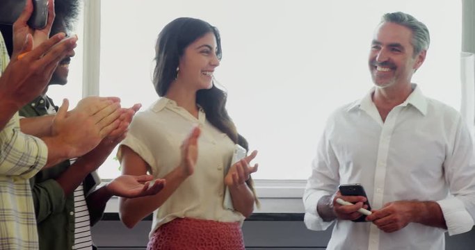 Executives applauding their colleague while giving presentation in office 