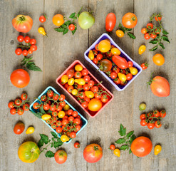 Fresh ripe tomatoes are in the box on wooden table. top view.