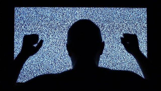 Man strikes in television screen. TV channel noise and black silhouette of man near television screen