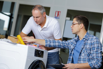 two plumber with clipboard fixing a washing machine