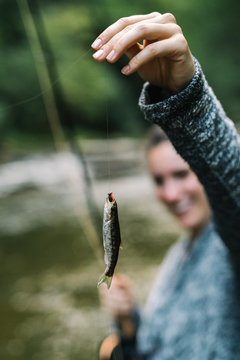 Woman smiling with very small fish caught on fly-fishing line