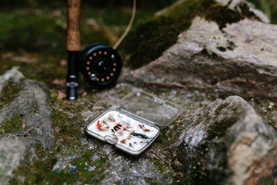 Fishing rod and reel with flies on side of river