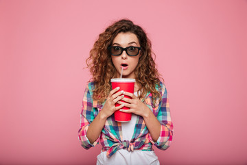 Shocked lady with cola and popcorn wearing 3d glasses