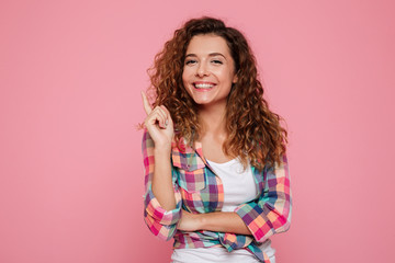 Happy young woman smiling and pointing at copy space