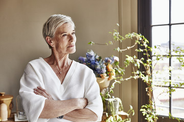 Happy Senior Woman Standing Arms Crossed At Home