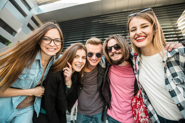 Casual stylish group of happy smiling students before modern building
