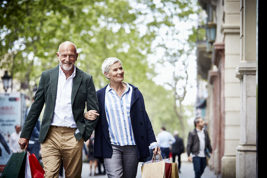 Senior Couple With Shopping Bags On Sidewalk