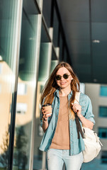 Fototapeta premium Hipster stylish girl wear sunglasses walk and hold cup of coffee