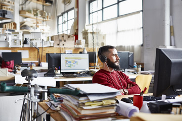 Thoughtful Businessman Wearing Headphones In Office
