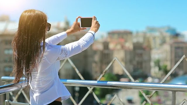 Businesswoman records videos on his smartphone. Woman makes photos on mobile phone. Attractive girl with red cell phone