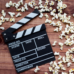 Watching the film. Movie clapperboard and popcorn on blue wooden table background top view copyspace