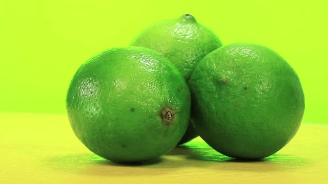 Green limes rotating on green background, citrus aurantiifolia