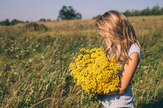 Woman holding big bouquet of yellow wildflowers