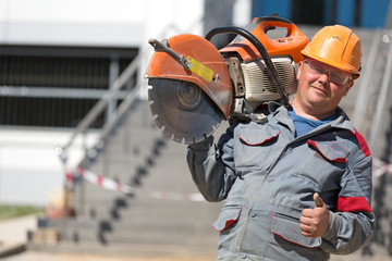 Construction man worker with petrol disc cutter gesturing ok sign outdoors