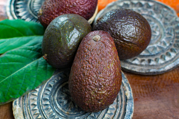 Healthy vegetarian food – green ripe avocado, new harvest, with leaves on stone plates with ornament