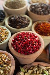 Variety of different spices with focus on pink Peruvian pepper, false pepper used in four peppers blends
