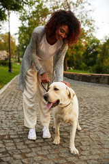 Happy lady hugging her white friendly dog while walking in park