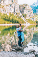Fototapeta na wymiar Young couple near lake lago di braies,Dolomite,Italy hold the hand stand at the stone at lake.