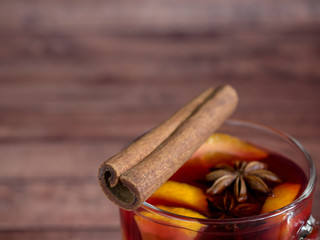 Glass Cup of red wine mulled wine on a wooden background with cinnamon spices and orange. Selective focus