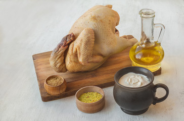 Carcass of raw chicken and oil with spices.