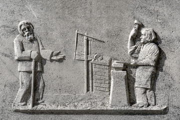 Beggar with outstretched arm and blacksmith with hammer and anvil, detail of an old tombstone in...
