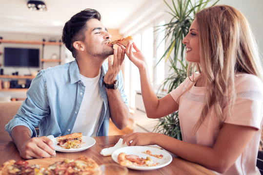 Happy young couple eating pizza at home